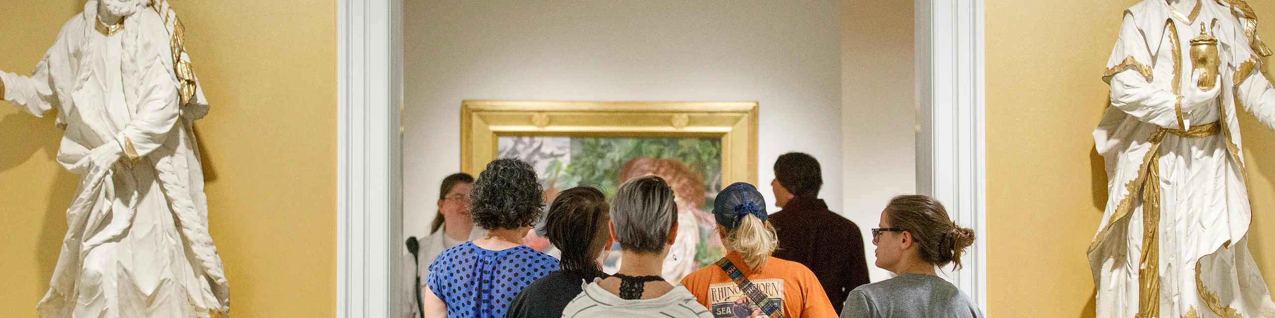 Students explore an art gallery, viewing exhibits and artwork framed by historic sculptures, highlighting the interdisciplinary learning opportunities available through KU's American studies degree.