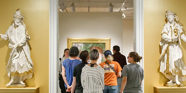 Students explore an art gallery, viewing exhibits and artwork framed by historic sculptures, highlighting the interdisciplinary learning opportunities available through KU's American studies degree.