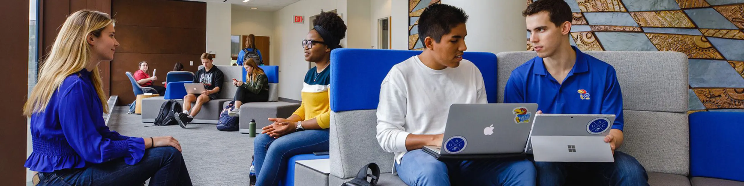 KU business students review online course materials on laptops.