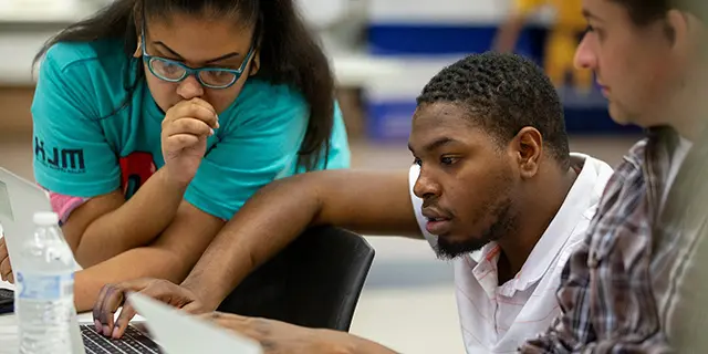Master of computer science students coding algorithms on laptops in a university of Kansas tech lab