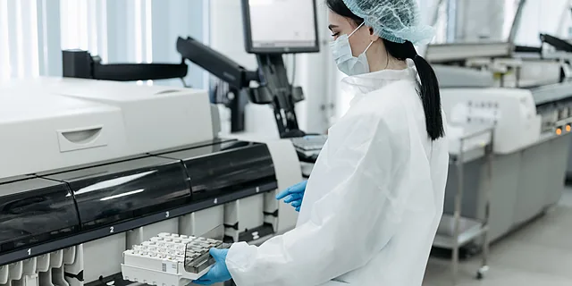 A KU diagnostic science degree student uses automated laboratory equipment to analyze clinical samples in a healthcare laboratory setting.