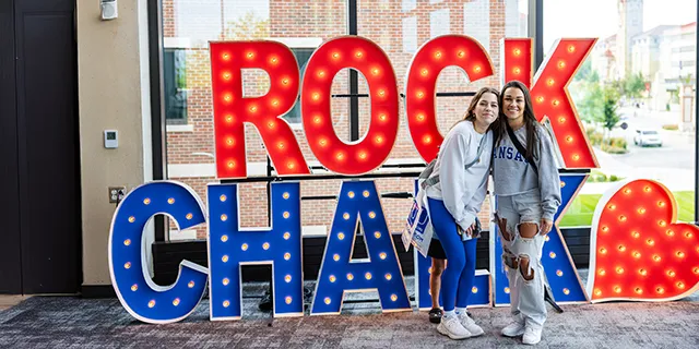 Linguistics degree students posing for a photo in front of a Rock Chalk sign