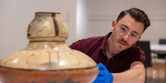 Master of museum studies student curating artifacts for a museum exhibit in the university of Kansas collections lab