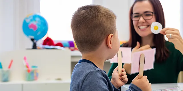 Master of speech language pathology student practicing speech therapy techniques with a child in a university of Kansas clinic simulation lab