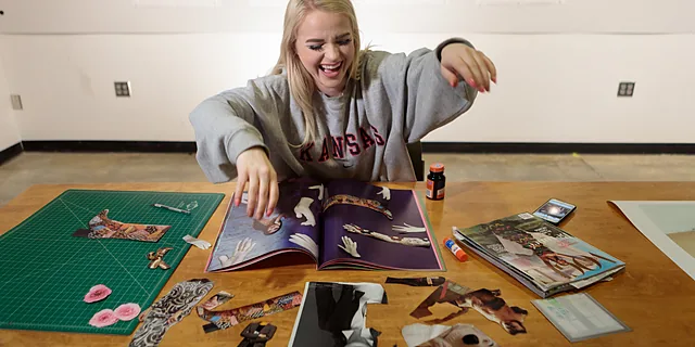 A KU fine arts degree student works on a collage project using photography, paper cutouts, and design techniques, demonstrating the creative and studio-based learning experience in the program.